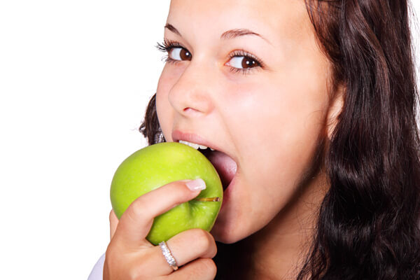 Девушка ест яблоко - зубная боль при кусании